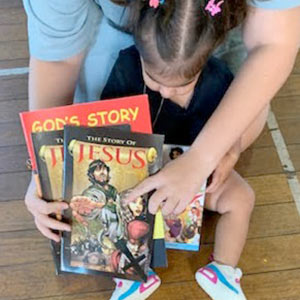 young girl holding bible story books